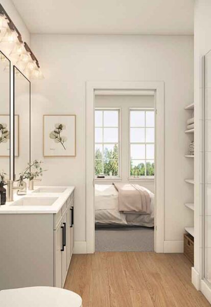 A well-lit bathroom with white cabinetry, a round mirror, and modern lighting, leading to a bedroom with a view of greenery through windows.