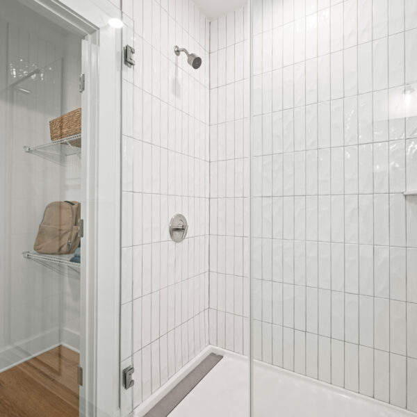 Glass shower in bathroom with white tile
