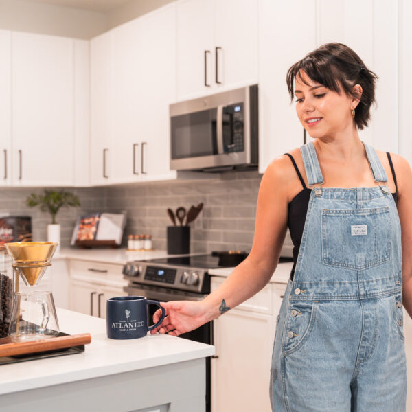 Girl grabbing coffee from counter in apartment kitchen.