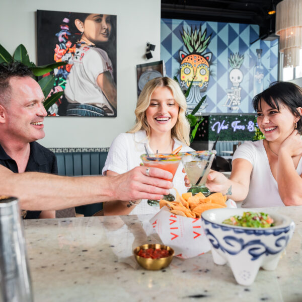 Friends enjoying cocktails and conversation at a local Daniel Island restaurant with colorful artwork in the background.
