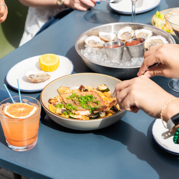 Close-up of shared dishes and drinks at an outdoor table at a Daniel Island restaurant.