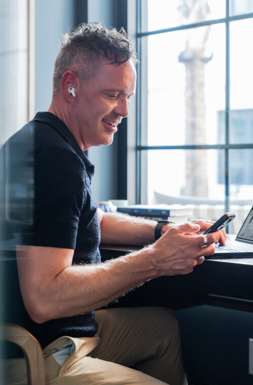 Man using a co-working pod with laptop and phone