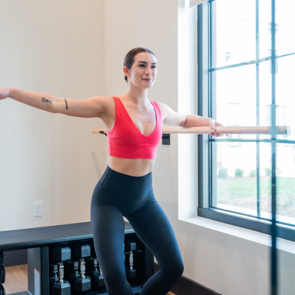 Resident practicing a barre workout in the bright yoga and barre studio with natural light filling the space.