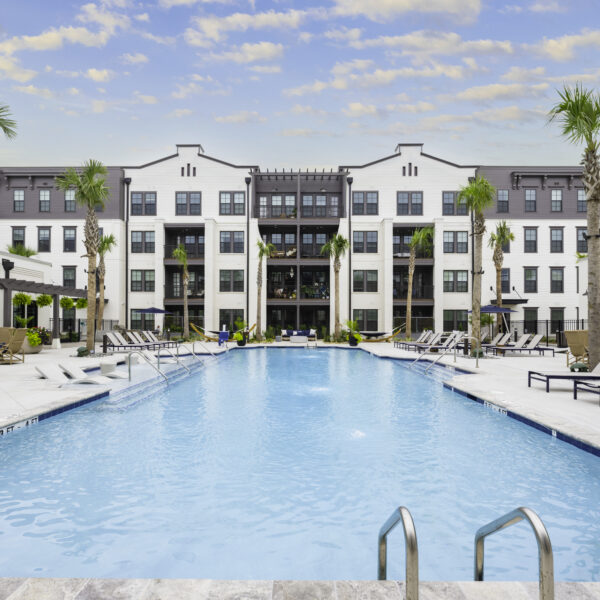 Community pool area with sundeck seating and tropical landscaping
