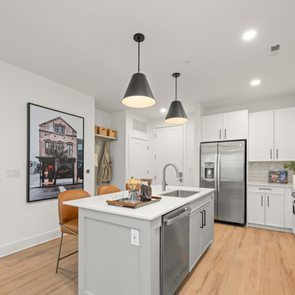 Bright kitchen with wood-style flooring, a stainless steel refrigerator, and a spacious island sink.