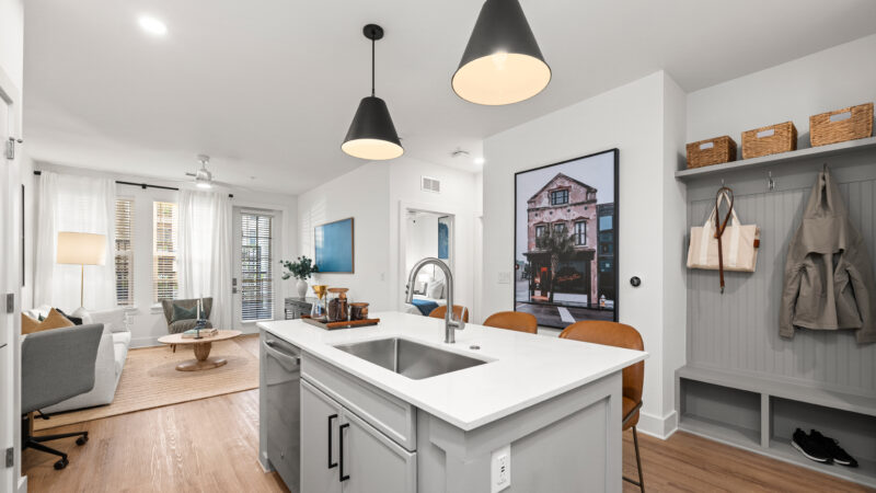 Open-concept kitchen featuring quartz countertops, bar seating with tan chairs, and sleek black hardware.