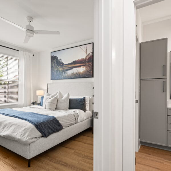 Modern bedroom with a textured headboard, woven nightstand, and large landscape photograph above the bed.
