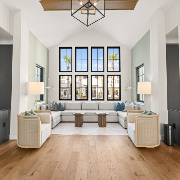 Bright common area featuring expansive windows, wood flooring, and multiple seating areas designed for gathering and relaxation.