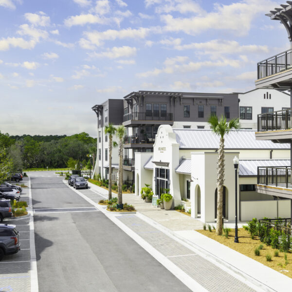 Exterior view of the Atlantic Nowell Creek leasing office with coastal-inspired architecture, white stucco finishes, and surrounding palm trees on Daniel Island.