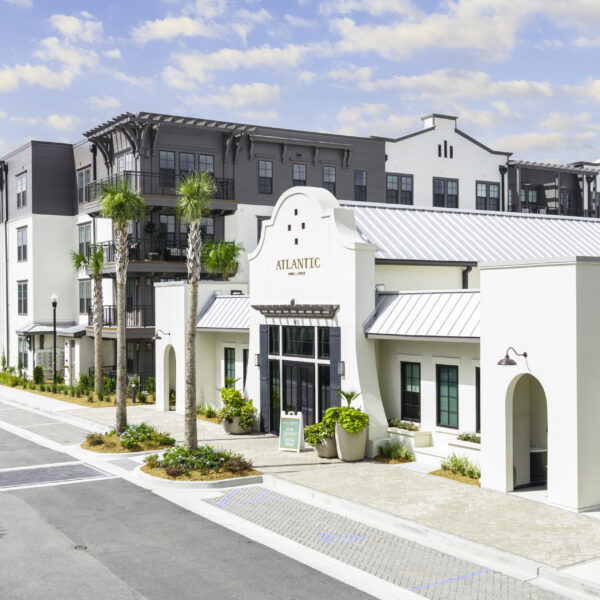 Front entrance of Atlantic Nowell Creek featuring arched walkways, metal roofing, and lush landscaping.